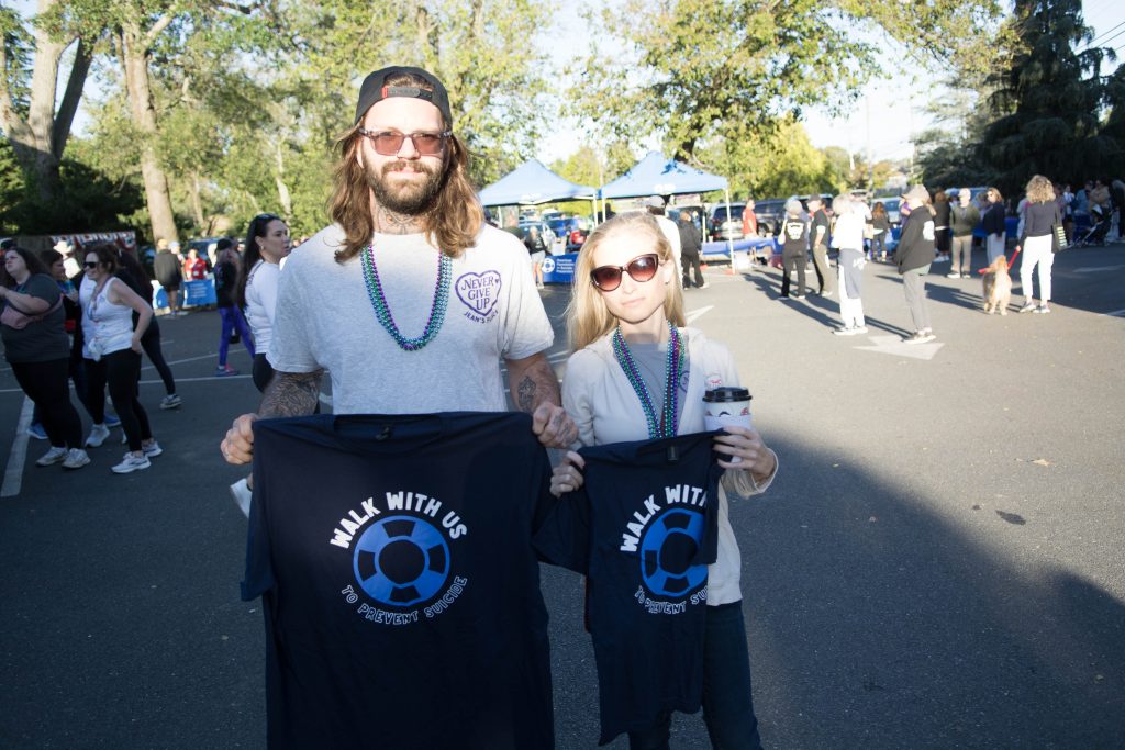 Dave and Cait holding up shirts that say "Walk with me to prevent suicide"