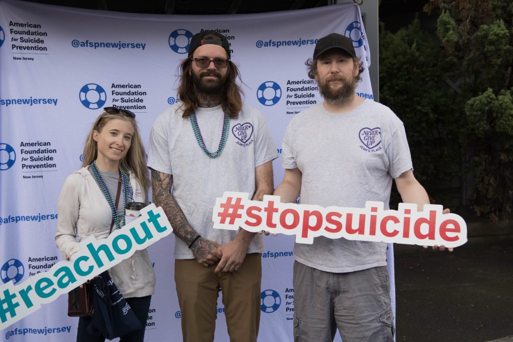 Cait holding a sign that says #reachout, Dave, and Jason holding a sign that says #stopsuicide